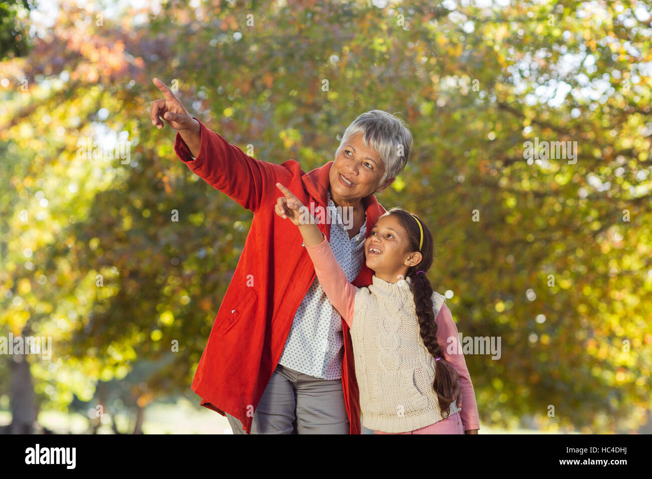 Enkelin mit Großmutter zeigt stehend im park Stockfoto