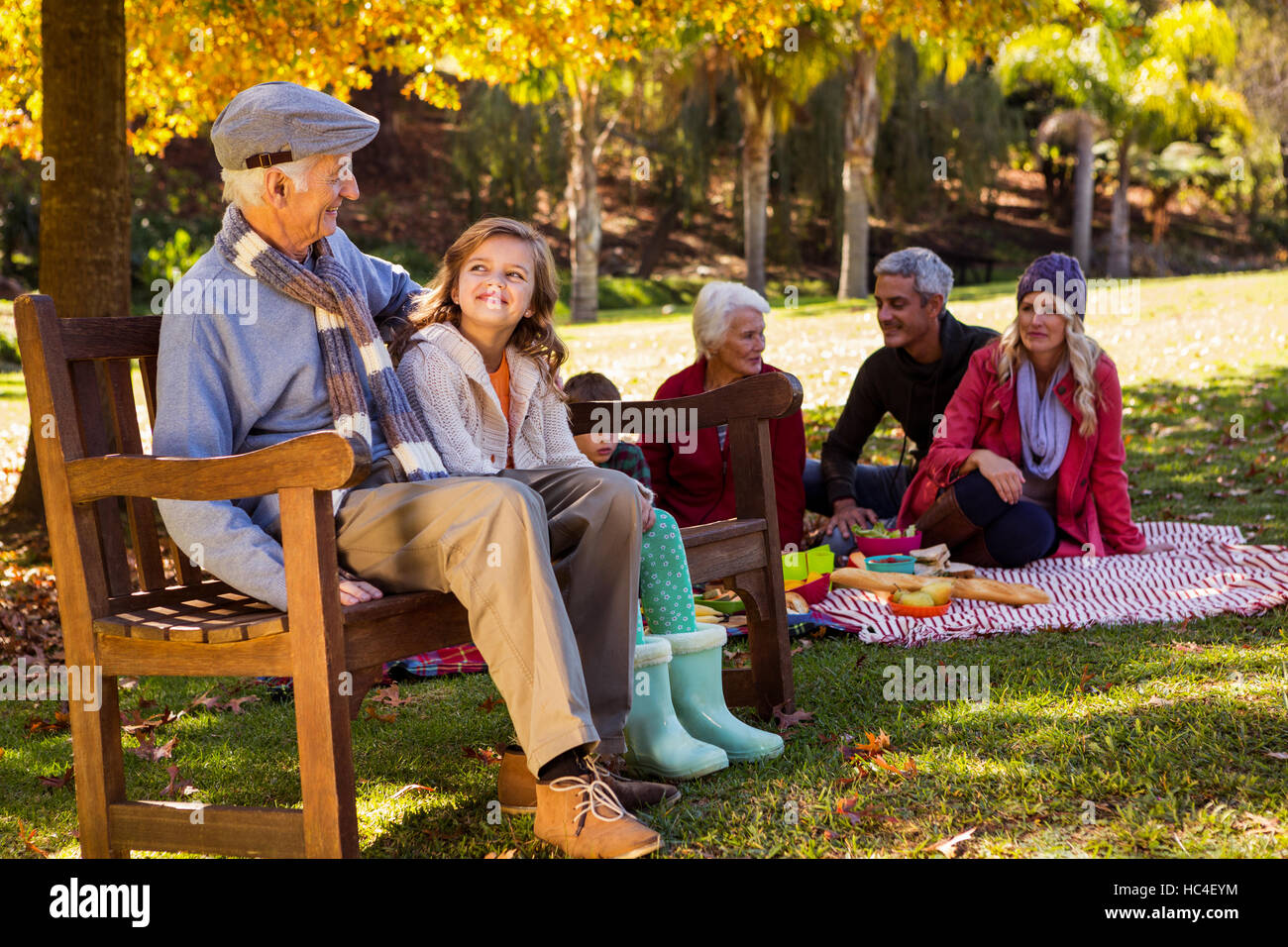 Familie picknicken und der Großvater mit seiner Enkelin auf einer Bank zu lachen Stockfoto