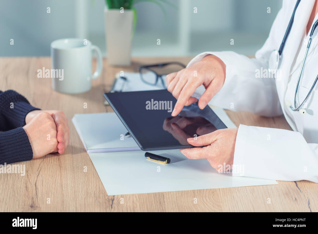 Ärztin, die Patienten mit Hilfe digitaler Tablet-Computer im Krankenhaus Büro ärztliche Untersuchung Ergebnisse vorlegen Stockfoto