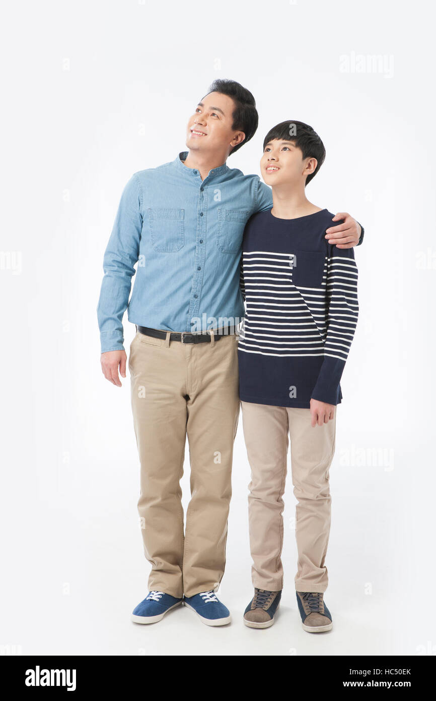 Lächelnd Mitte im Alter Vater und heranwachsenden Sohn mit Arme auf die Schultern nach oben stehend Stockfoto