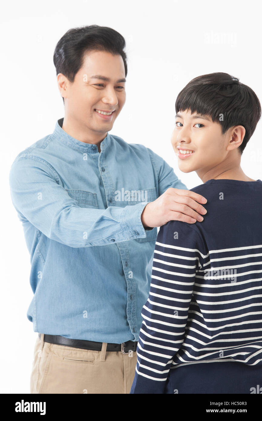 Lächelnd Mitte im Alter Vater seinen Jugendlichen Sohn auf der Schulter berühren Stockfoto