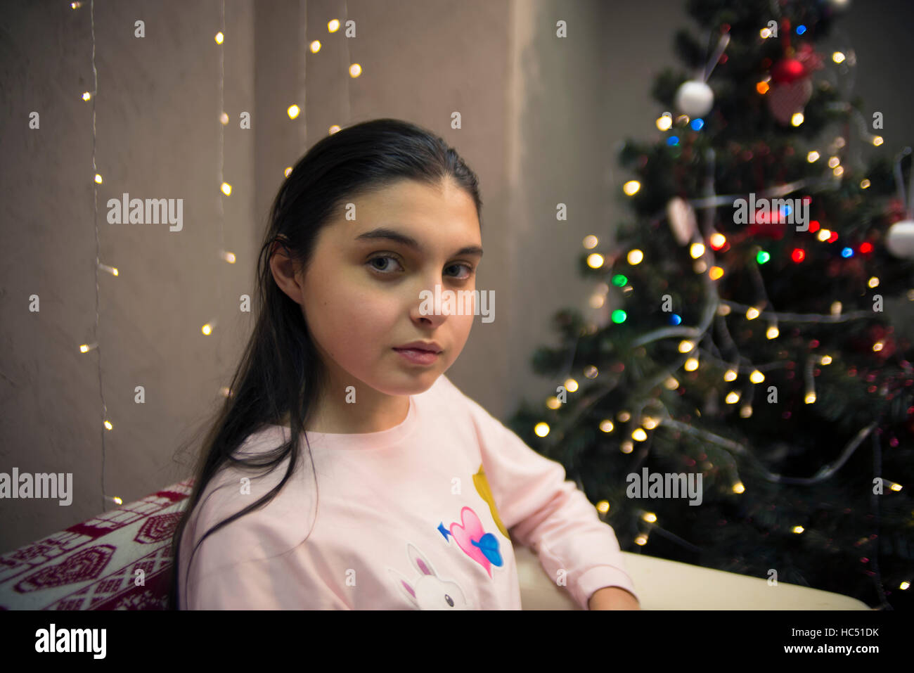 ernsthafte Teen Mädchen sitzt auf dem Sofa in der Nähe der Weihnachtsbaum Stockfoto