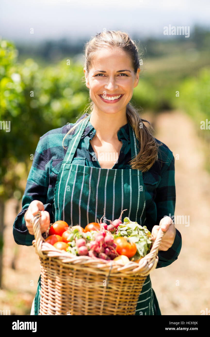 Porträt von glücklich Bäuerin hält einen Korb mit Gemüse Stockfoto