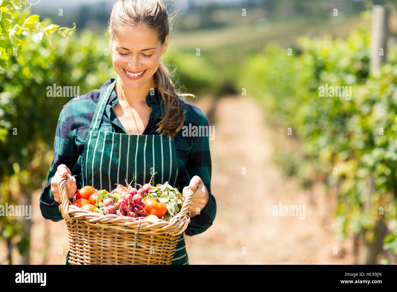 Glücklich Bäuerin hält einen Korb mit Gemüse Stockfoto