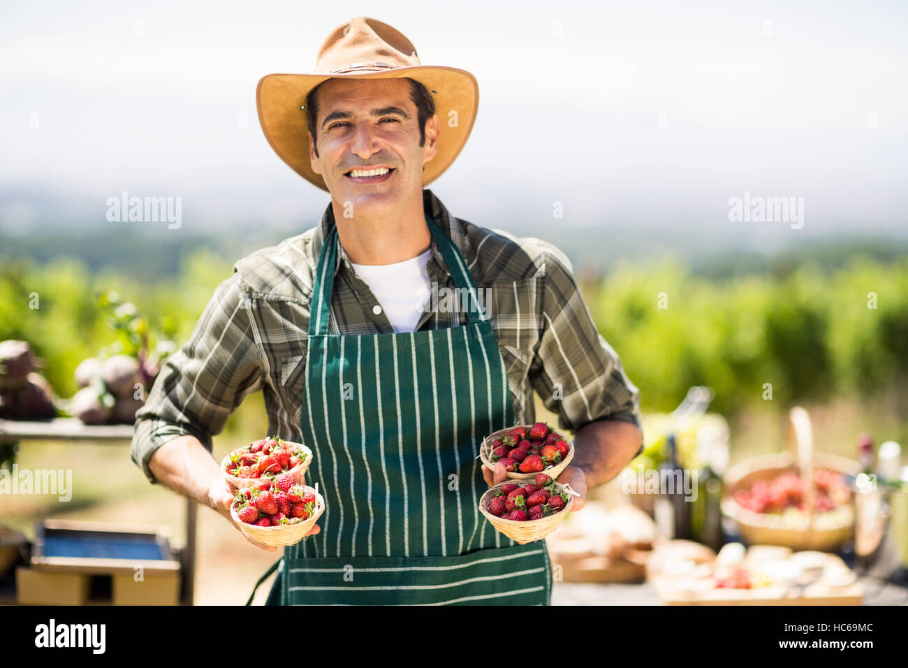 Porträt eines lächelnden Bauern halten Schalen Erdbeeren Stockfoto