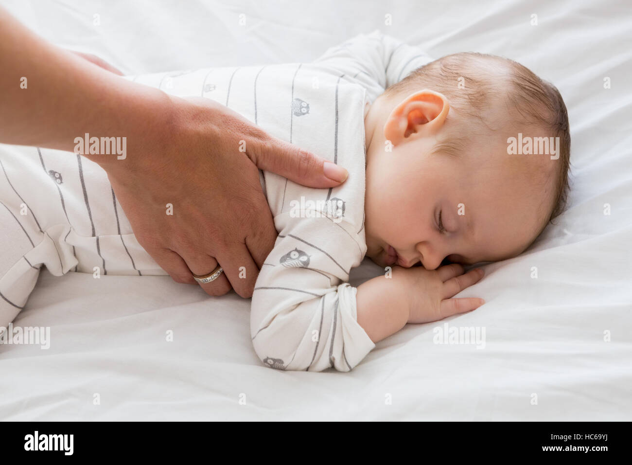 Mutter putting Baby im Babybett schlafen Stockfoto