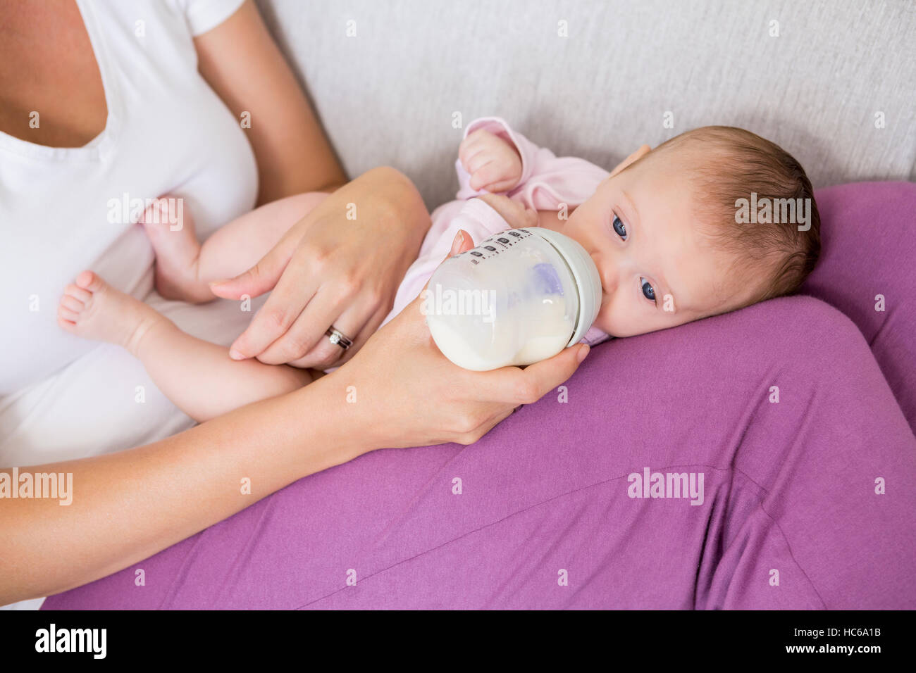 Mutter Fütterung Baby mit Milchflasche im Wohnzimmer Stockfoto