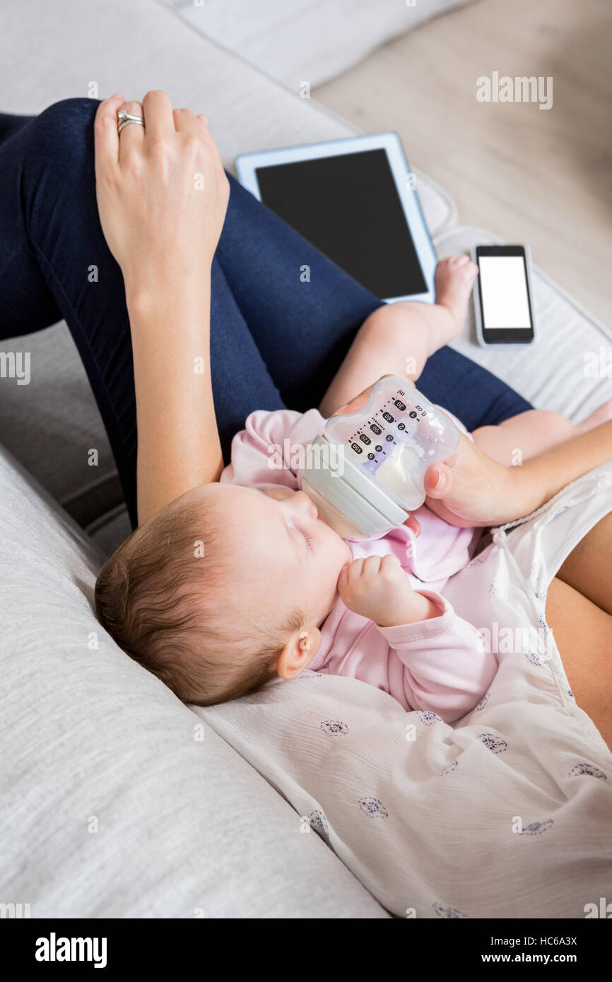 Mutter, füttern ihr Baby mit Milchflasche im Wohnzimmer Stockfoto