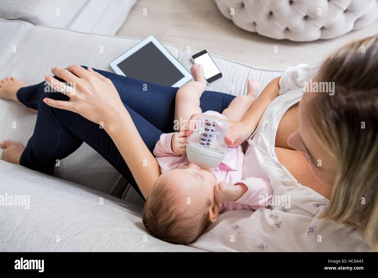 Mutter, füttern ihr Baby mit Milchflasche im Wohnzimmer Stockfoto