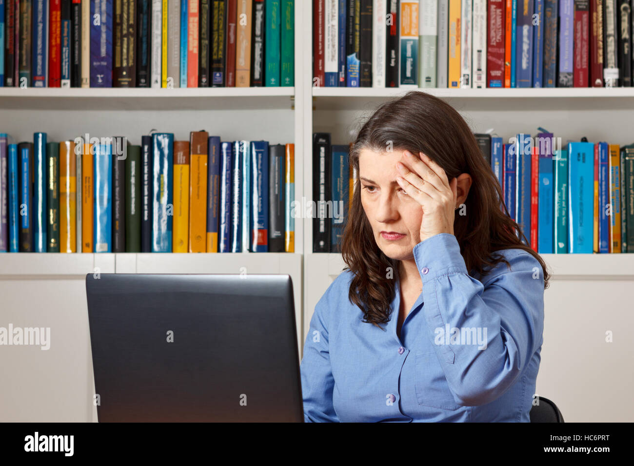 Reife Frau vor einem Computer im Büro drücken eine Hand an ihre Stirn, Kopfschmerzen, Migräne, stress Stockfoto
