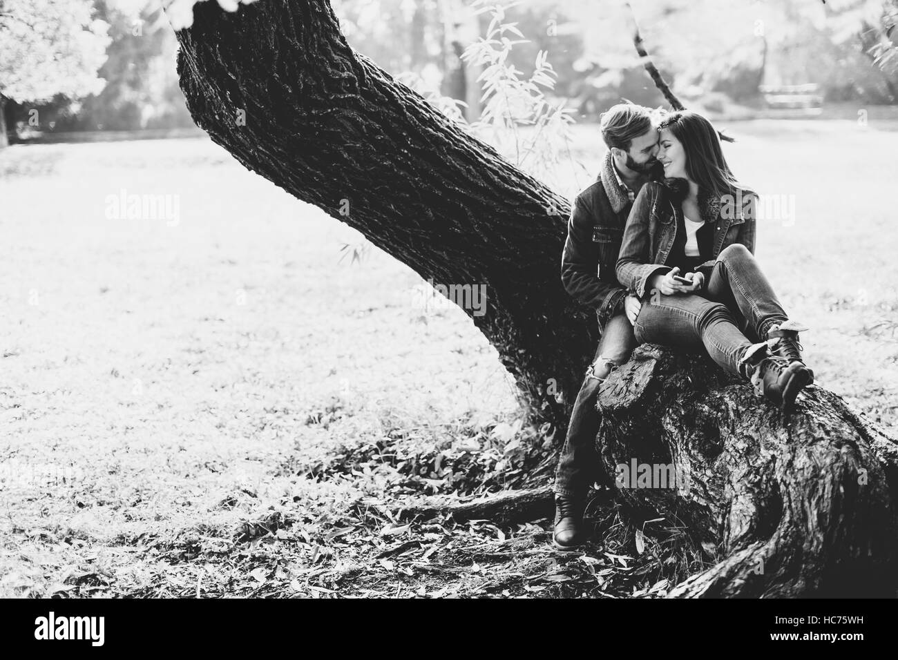 Paar in Liebe sitzt auf einem Baum im Herbst park Stockfoto