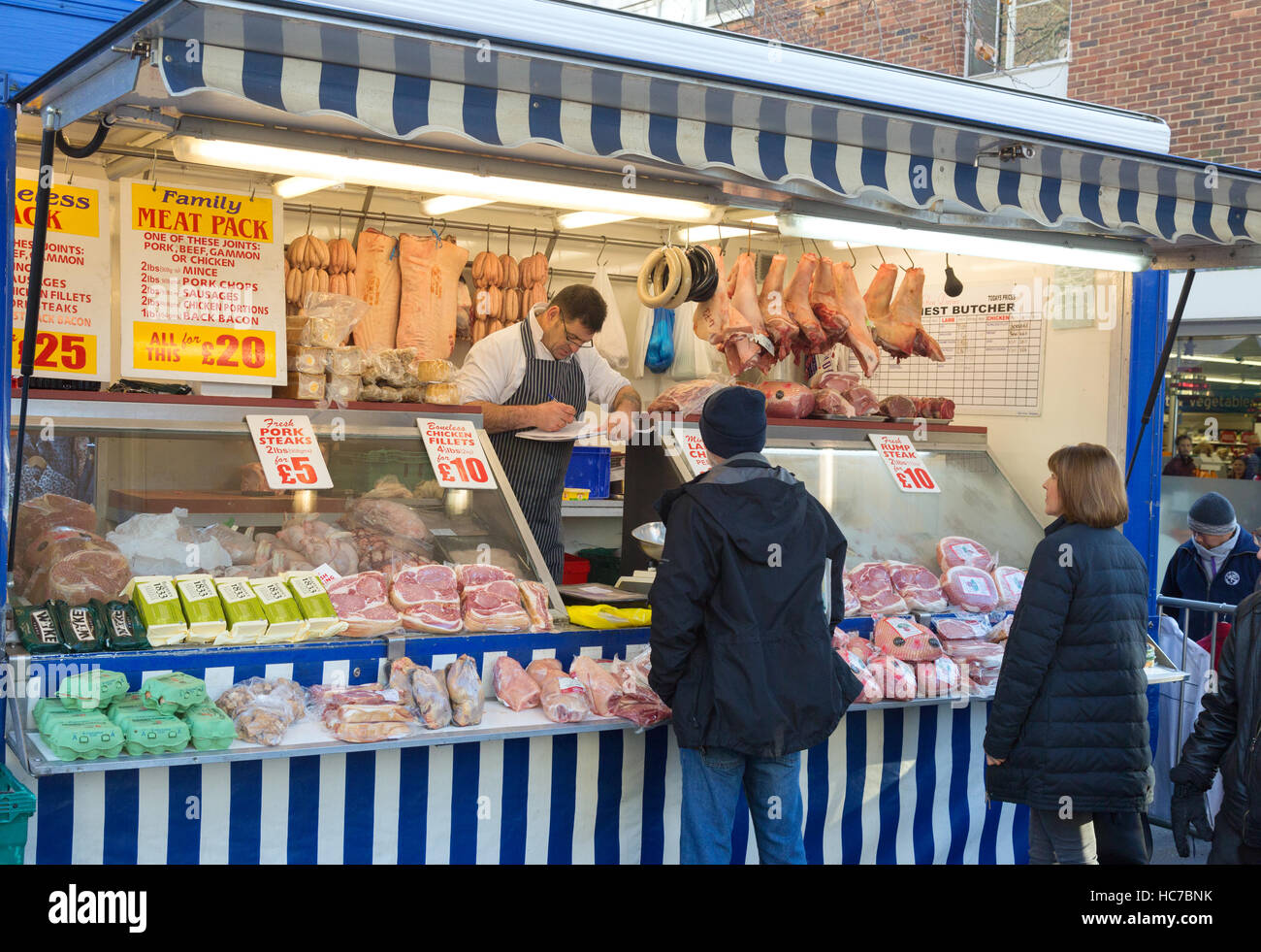 Menschen, die Einkaufen bei einem Metzger Stall, Winchester Markt, Winchester, Hampshire England UK Stockfoto