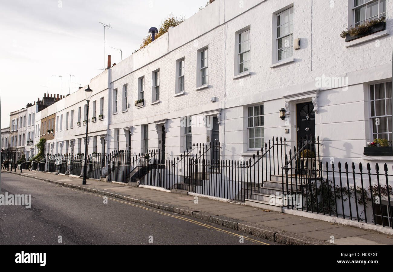 Blick auf eine leere Straße im Wohngebiet von Chelsea, London, Großbritannien mit viktorianischen weißen Wohngebäuden mit schwarzen Türen und Metallzaun. Stockfoto