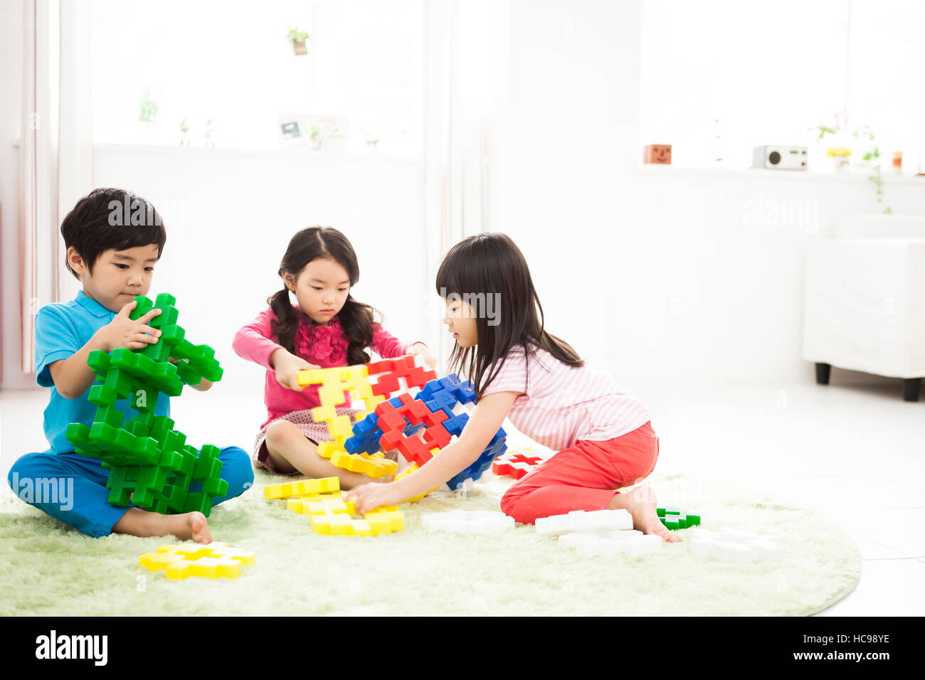 Drei Kinder spielen mit Blöcken im Innenbereich Stockfoto