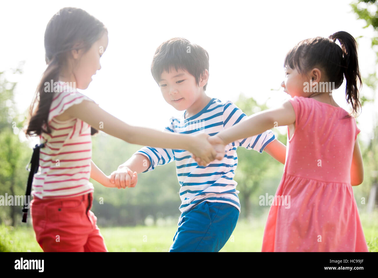 Drei lachende Kinder spielen im Feld Stockfoto