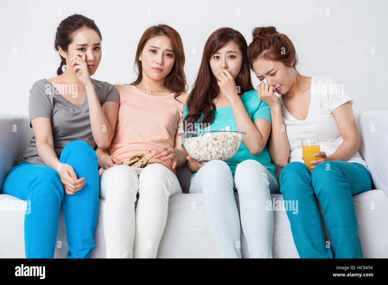 Vier junge Frauen fallen Tränen vor dem Fernseher zusammen Stockfoto