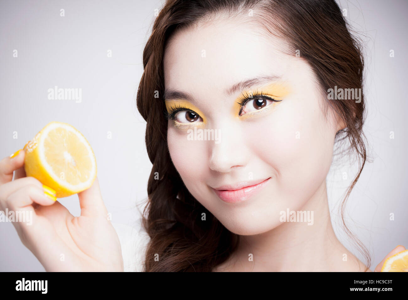 Porträt des jungen lächelnd Koreanerin in gelben Lidschatten posiert mit Zitrone Stockfoto