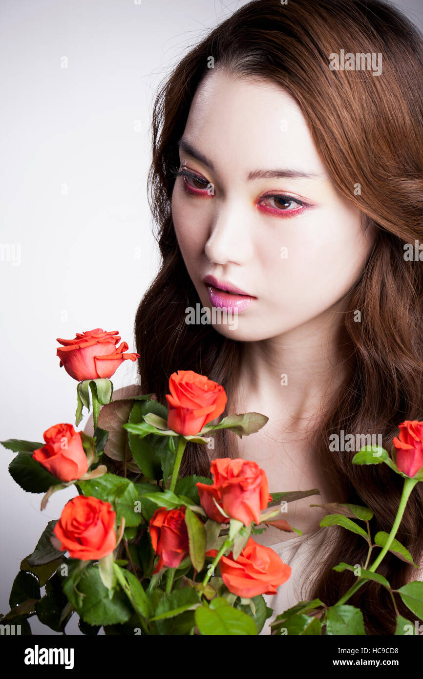 Porträt der jungen Frau mit roten Augen und rote Rosen Stockfoto