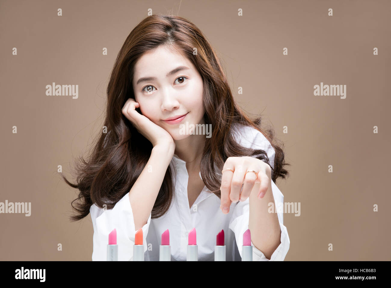 Porträt der jungen Frau mit Lippenstiften in Folge Stockfoto