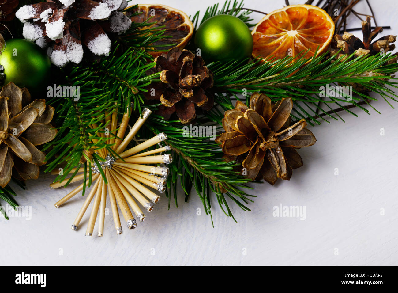Weihnachtsbaum-Zweige mit Stroh Sterne und Tannenzapfen. Weihnachten Hintergrund mit getrockneten Orangenscheiben und rustikalen Ornamenten. Stockfoto