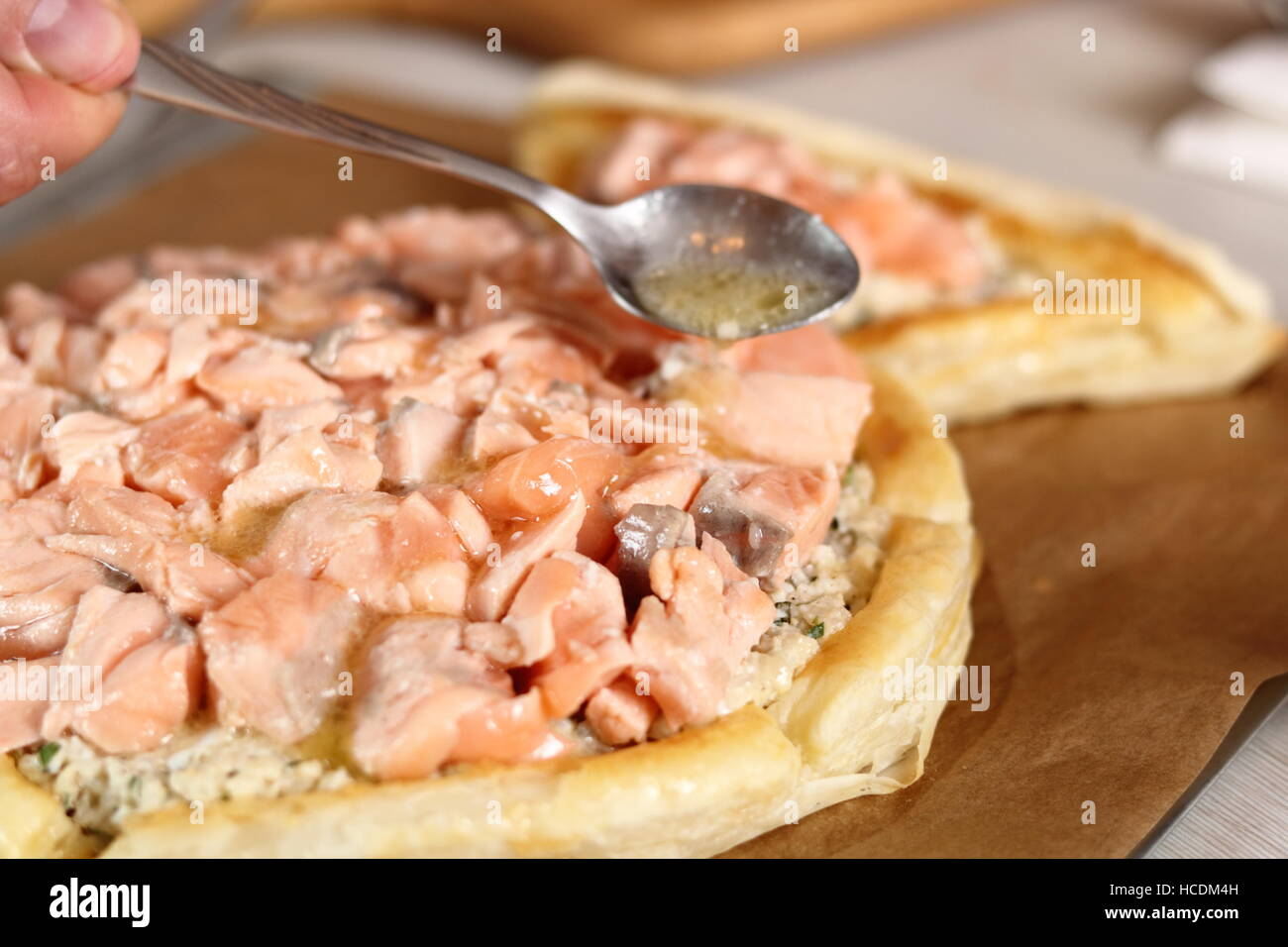 Löffel Saft von Zitrone und Butter aus Braten Lachs über Füllung. Lachs in Blätterteig-Serie zu machen. Stockfoto