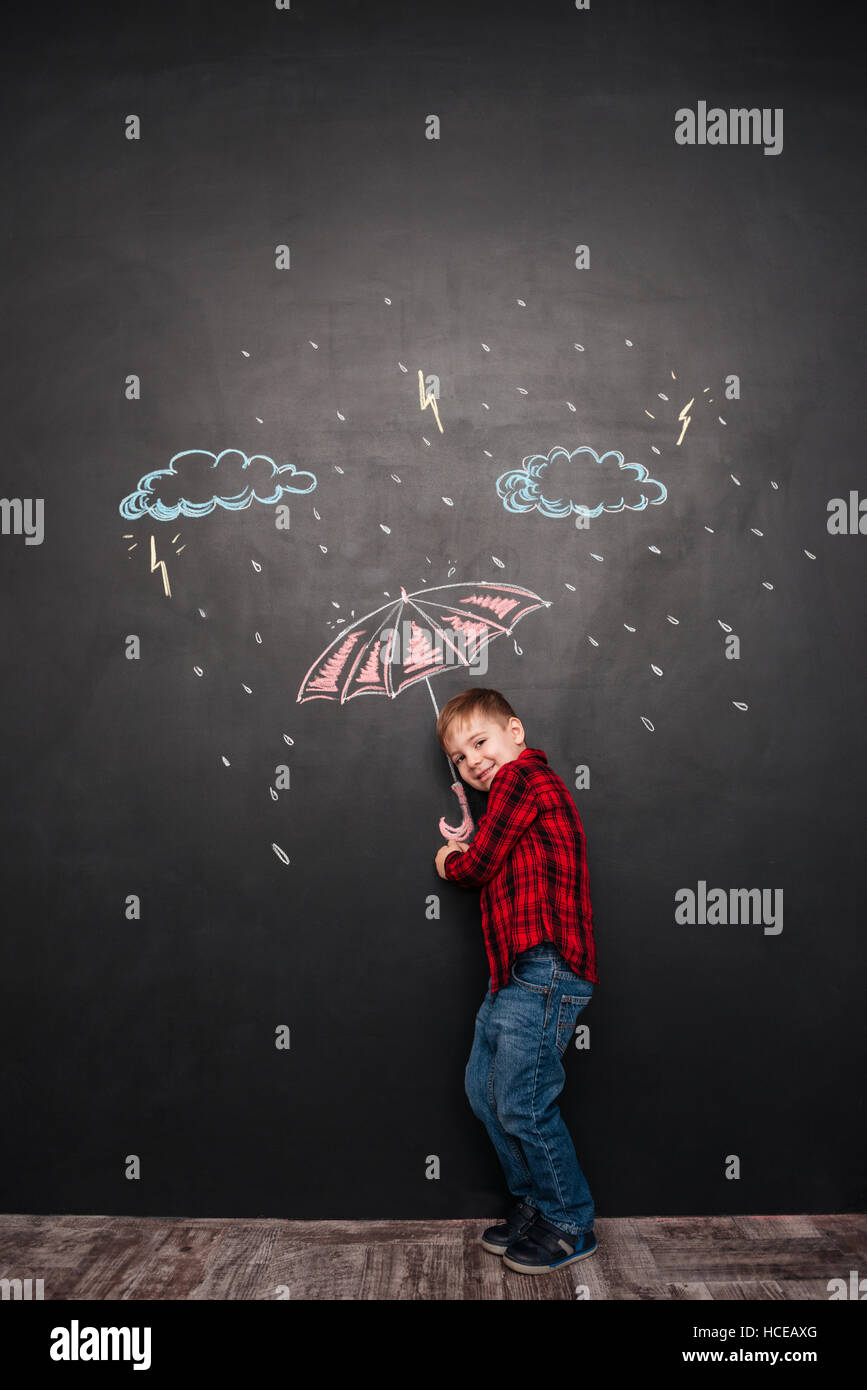 Foto von fröhlichen Geißlein Blick in die Kamera halten Dach an die Tafel mit Zeichnungen von einem Regen. Stockfoto