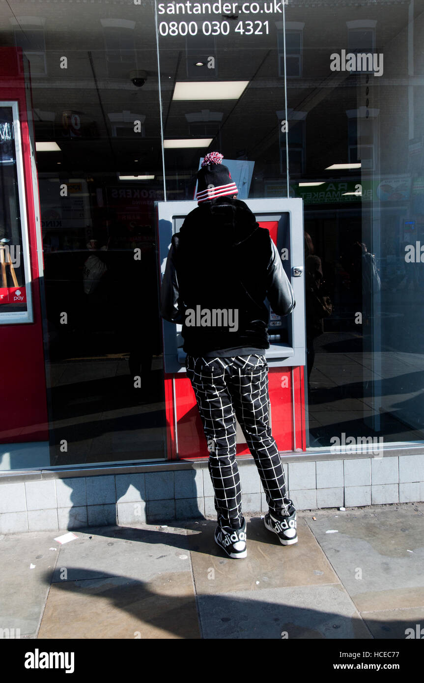 Hackney. Mann trägt kühn entworfen schwarzen und weiße Hosen am Geldautomat, Santander Bank, Kingsland Road. Stockfoto