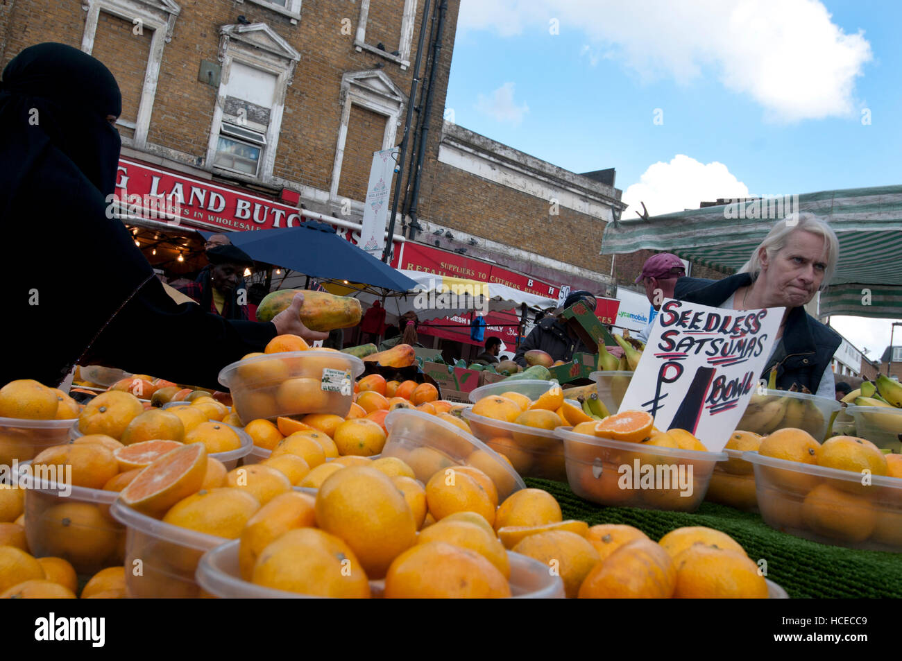 Hackney. Ridley Straße Markt. Obst-Stall. Eine Frau trägt einen durchgehenden schwarzen Schleier kauft eine papaya Stockfoto
