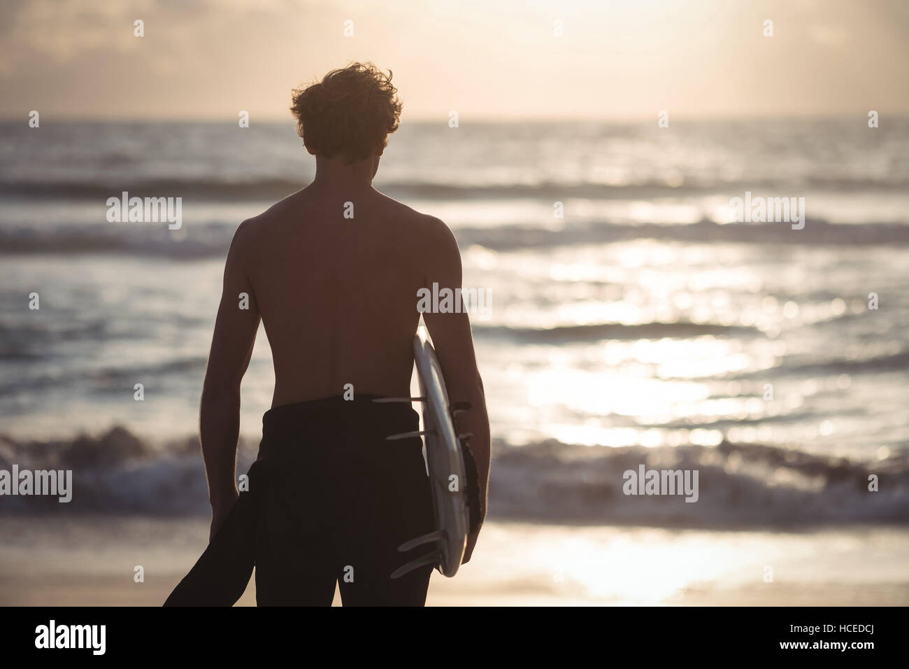 Mann mit Surfbrett stehend am Strand Stockfoto