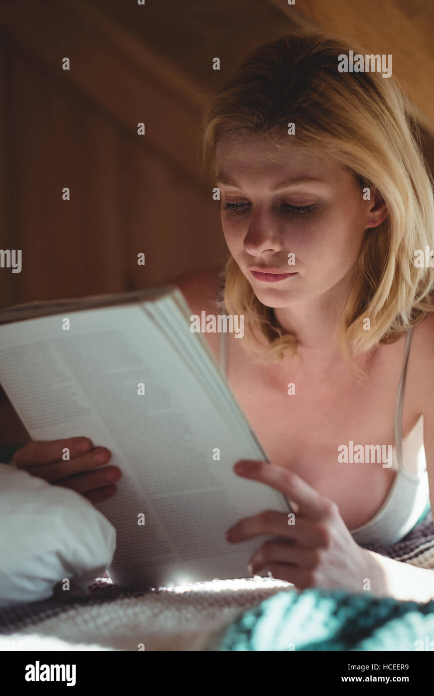 Schöne Frau am Bett liegen und lesen Magazin im Schlafzimmer Stockfoto