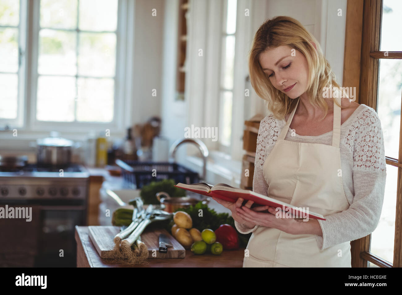 Schöne Frau liest Rezeptbuch in Küche Stockfoto