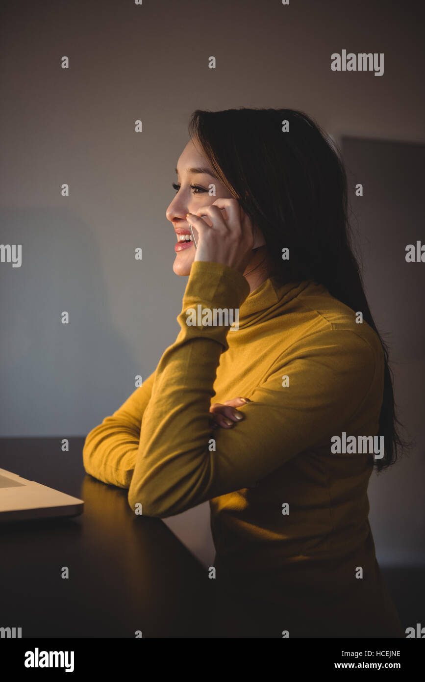 Frau am Handy während der Arbeit am laptop Stockfoto