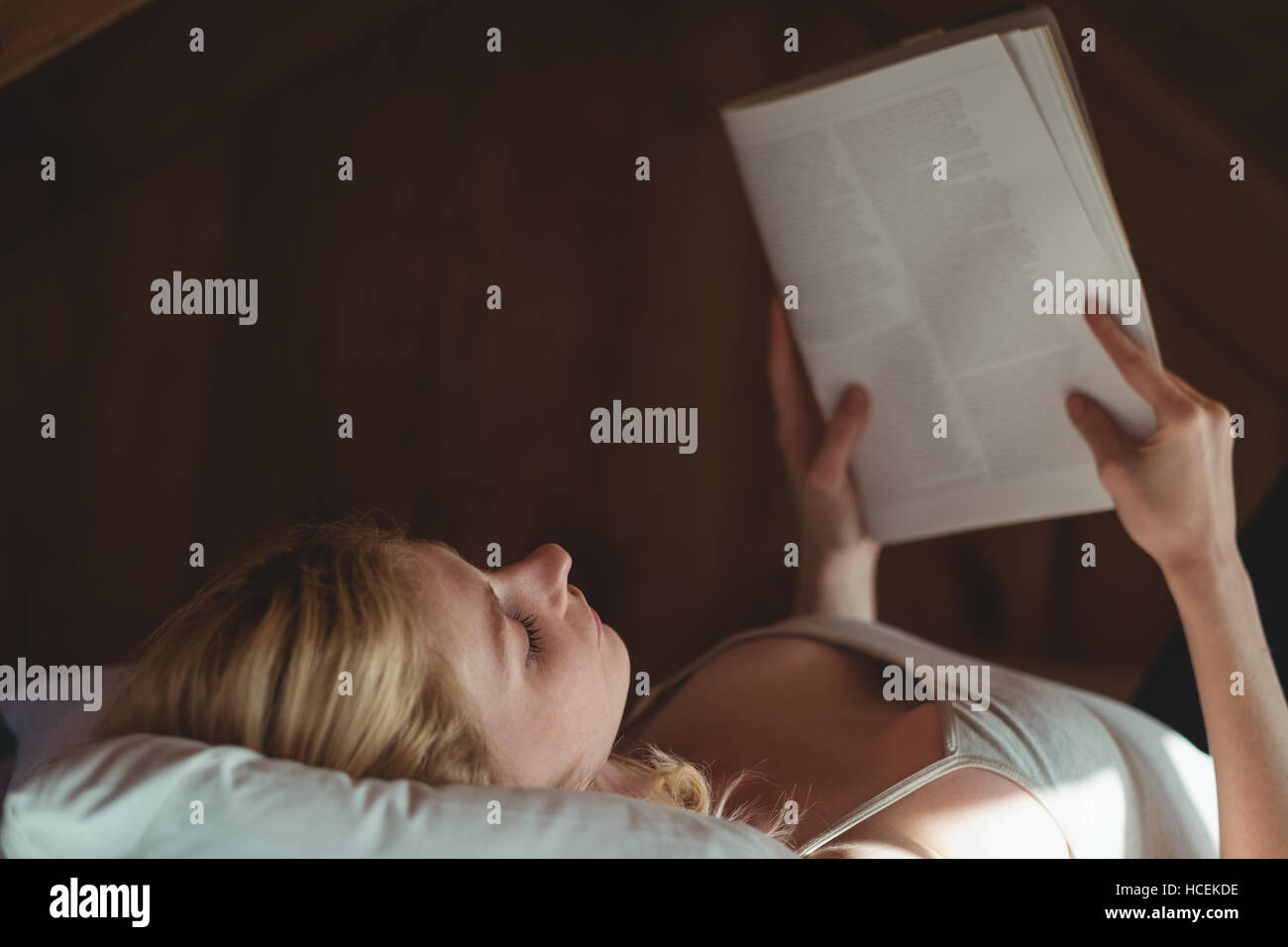 Schöne Frau am Bett liegen und lesen Magazin im Schlafzimmer Stockfoto