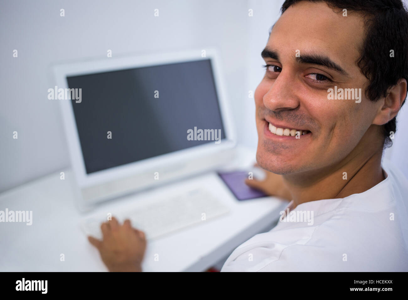 Lächelnde Arzt mit Desktop-pc in Klinik Stockfoto