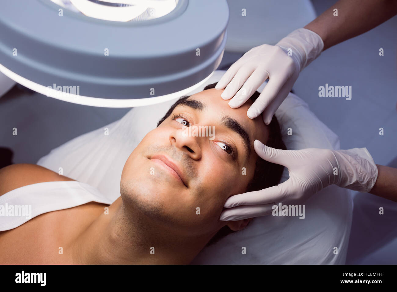 Arzt untersucht mans Gesicht für kosmetische Behandlungen Stockfoto