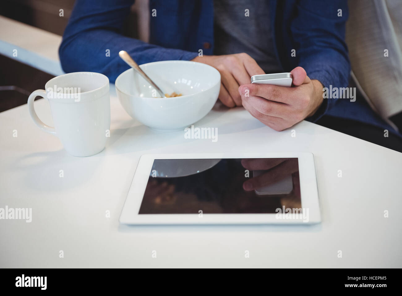 Mann mit Handy beim Frühstück in der Küche Stockfoto