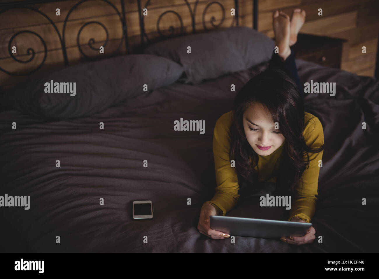 Frau auf Bett mit digital-Tablette im Schlafzimmer Stockfoto