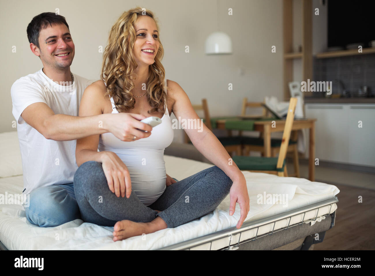 Werdende Mutter und Ehemann zu Hause vor dem Fernseher Stockfoto