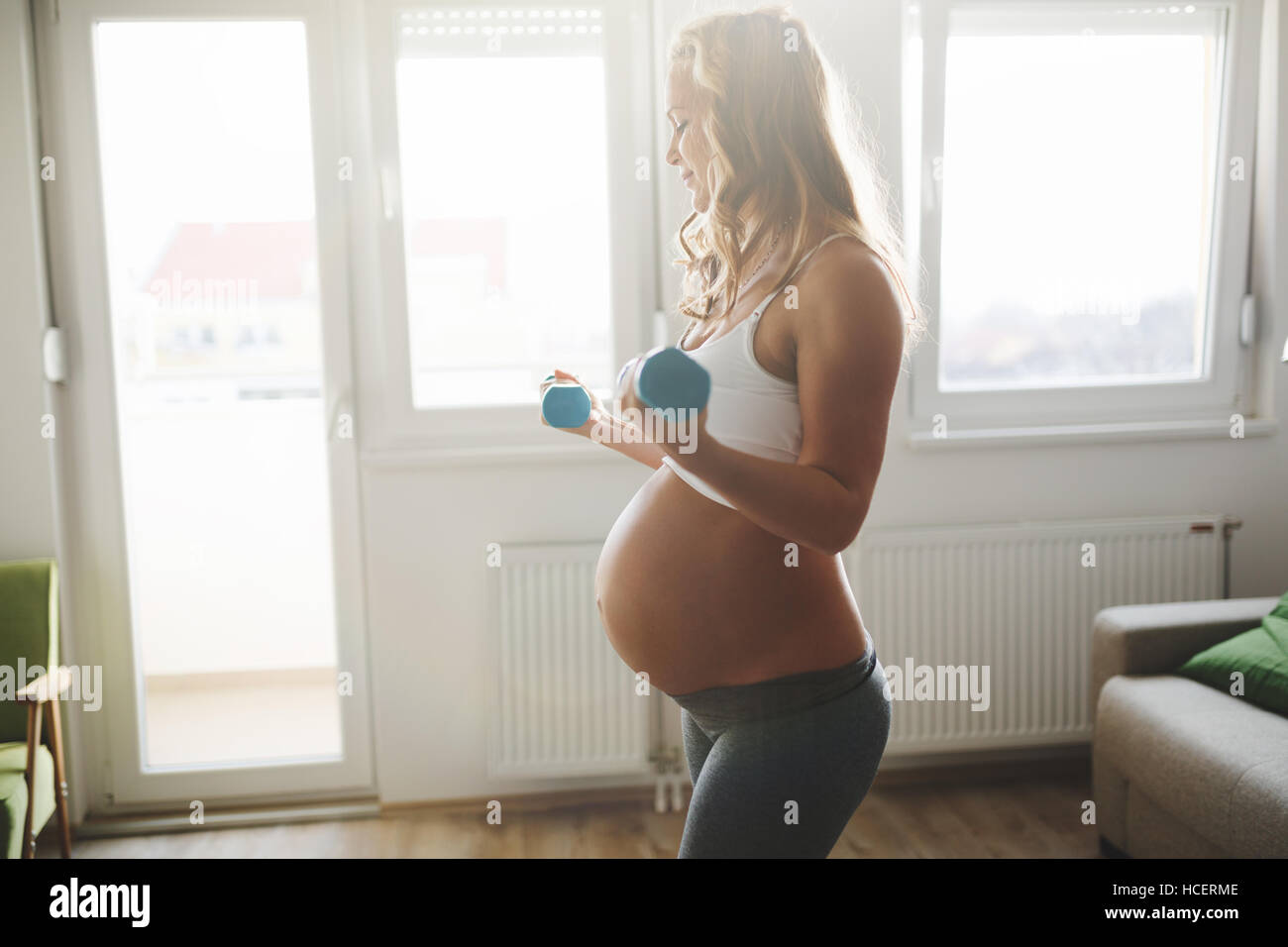 Sportliche schwangere Frau, die das Training mit Hanteln Stockfoto