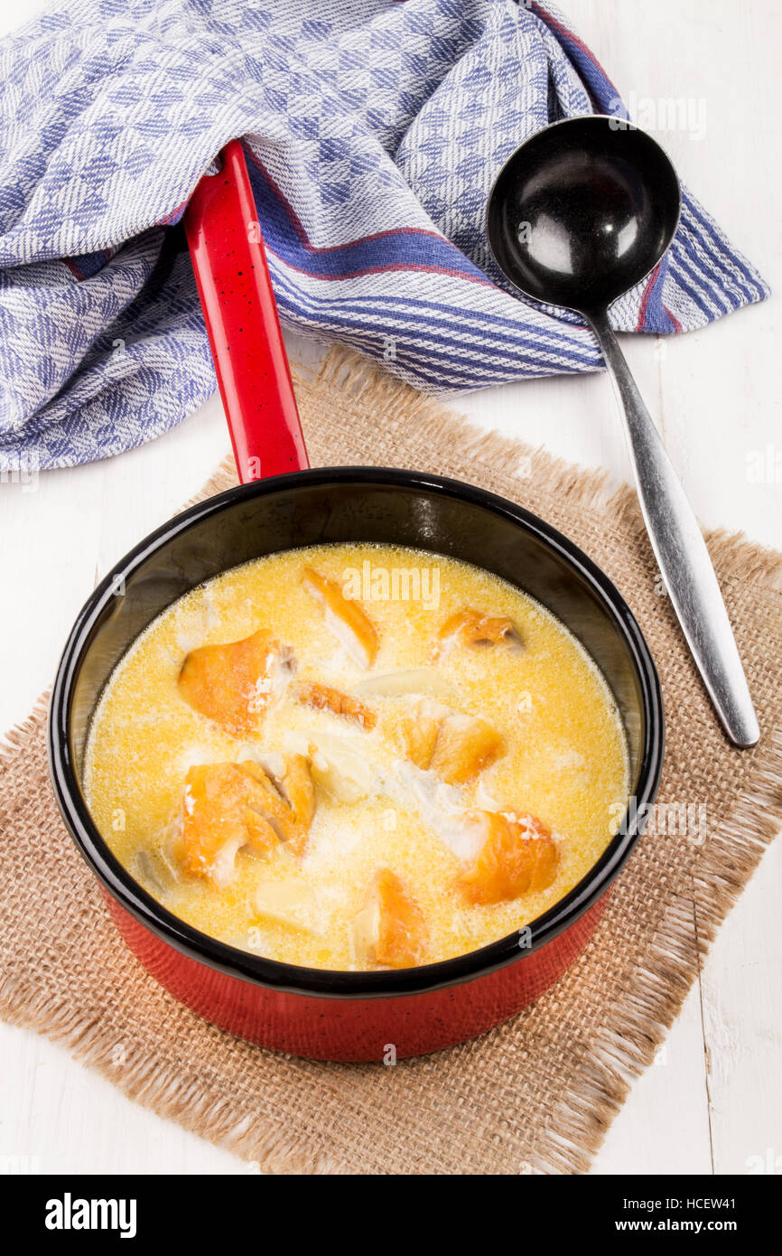 frisch zubereitete traditionelle schottische Fischsuppe, Cullen Skink, in einem roten Emaille-Topf mit Kelle auf jute Stockfoto