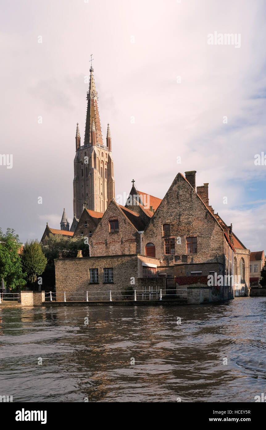Sint-Janshospitaal, Saint John's Hospital, Brügge. Im 12. Jahrhundert, gesehen aus dem Kanal mit dem Turm der Onze-Lieve-Vrouwekerk oder Kirche begonnen Stockfoto