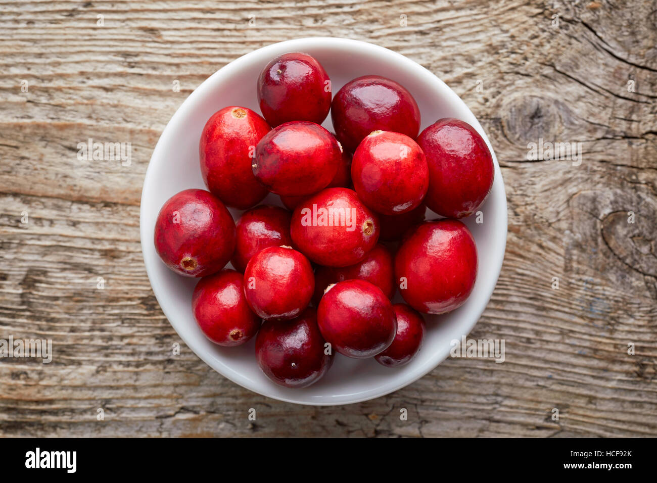 Schüssel mit Preiselbeeren auf hölzernen Hintergrund, Ansicht von oben Stockfoto
