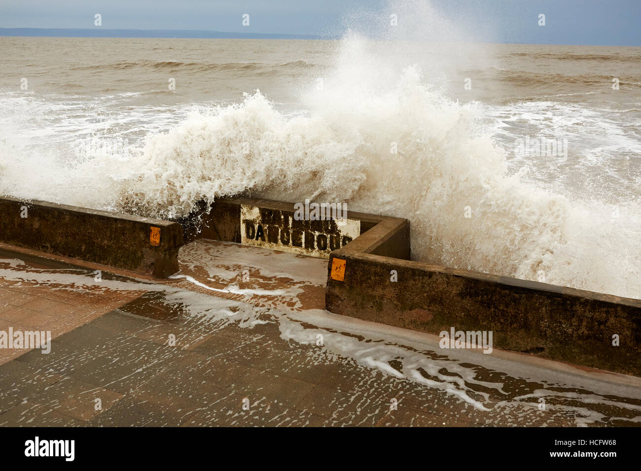 Wellen, die über Deich und "Baden gefährlich" zu unterzeichnen, Porthcawl, Wales, UK Stockfoto