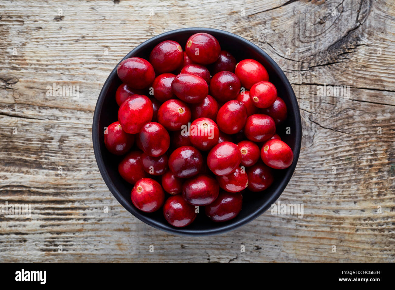 Schüssel mit Preiselbeeren auf hölzernen Hintergrund, Ansicht von oben Stockfoto