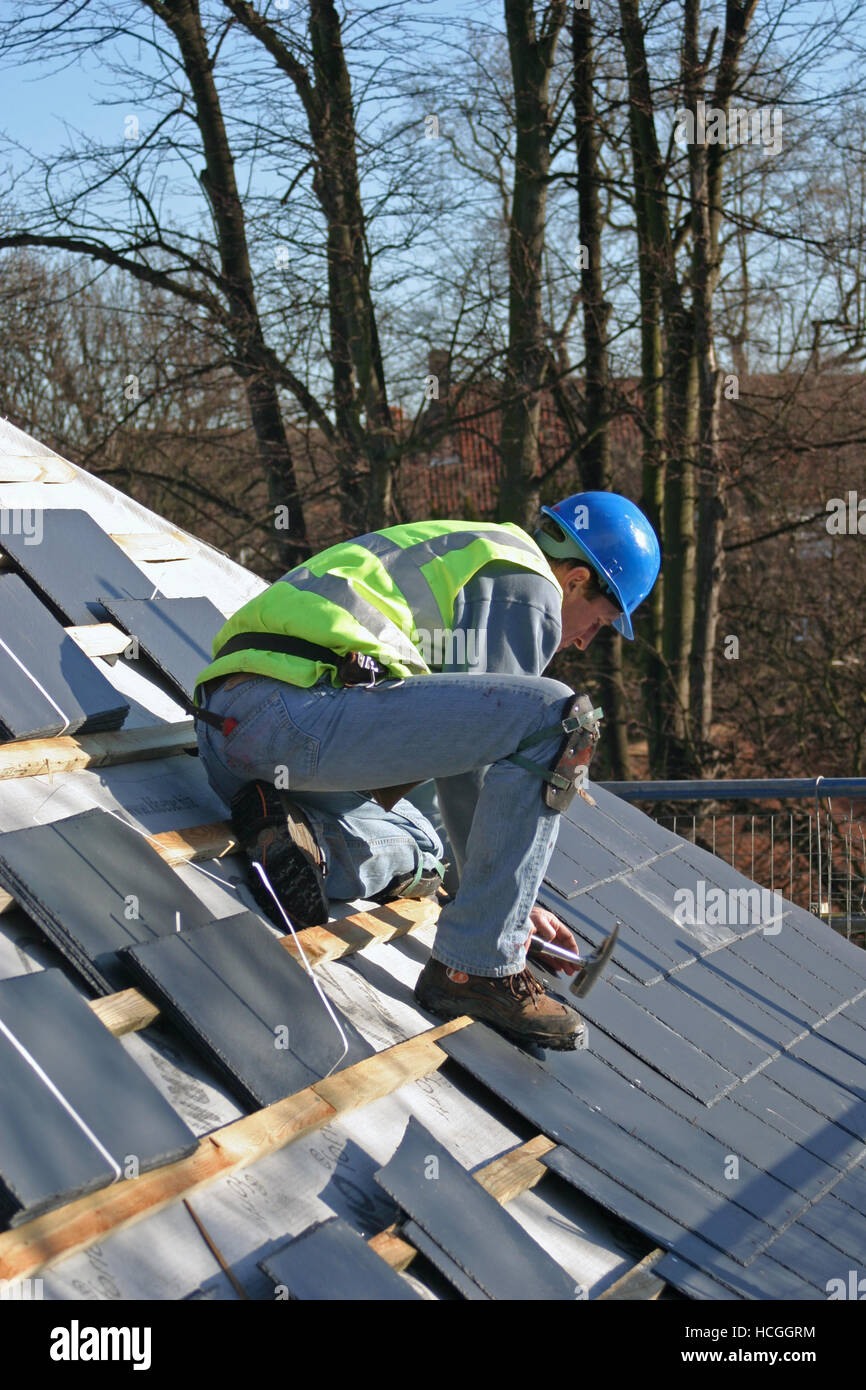 Dachdecker Nägel Schiefer über Holz Latten und Dachpappe auf einer neuen Wohnsiedlung in Richmond, Süd-London, UK. Stockfoto