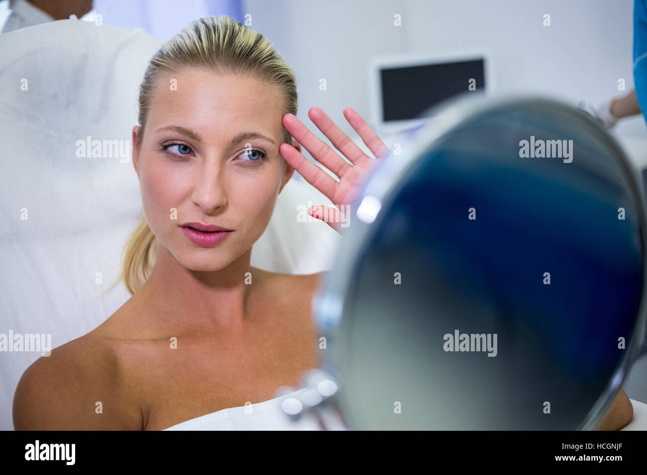Frau, die Überprüfung ihrer Haut in den Spiegel nach einer kosmetischen Behandlung Stockfoto