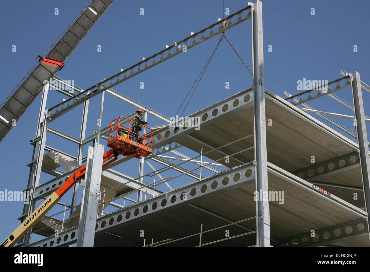 PPE ausgestattete Bauarbeiter im Cherry Picker Einbau PCC precast Planken in kronenmutter Stahl Rahmen auf dem neuen Parkplatz Bauvorhaben Bolton GROSSBRITANNIEN Stockfoto