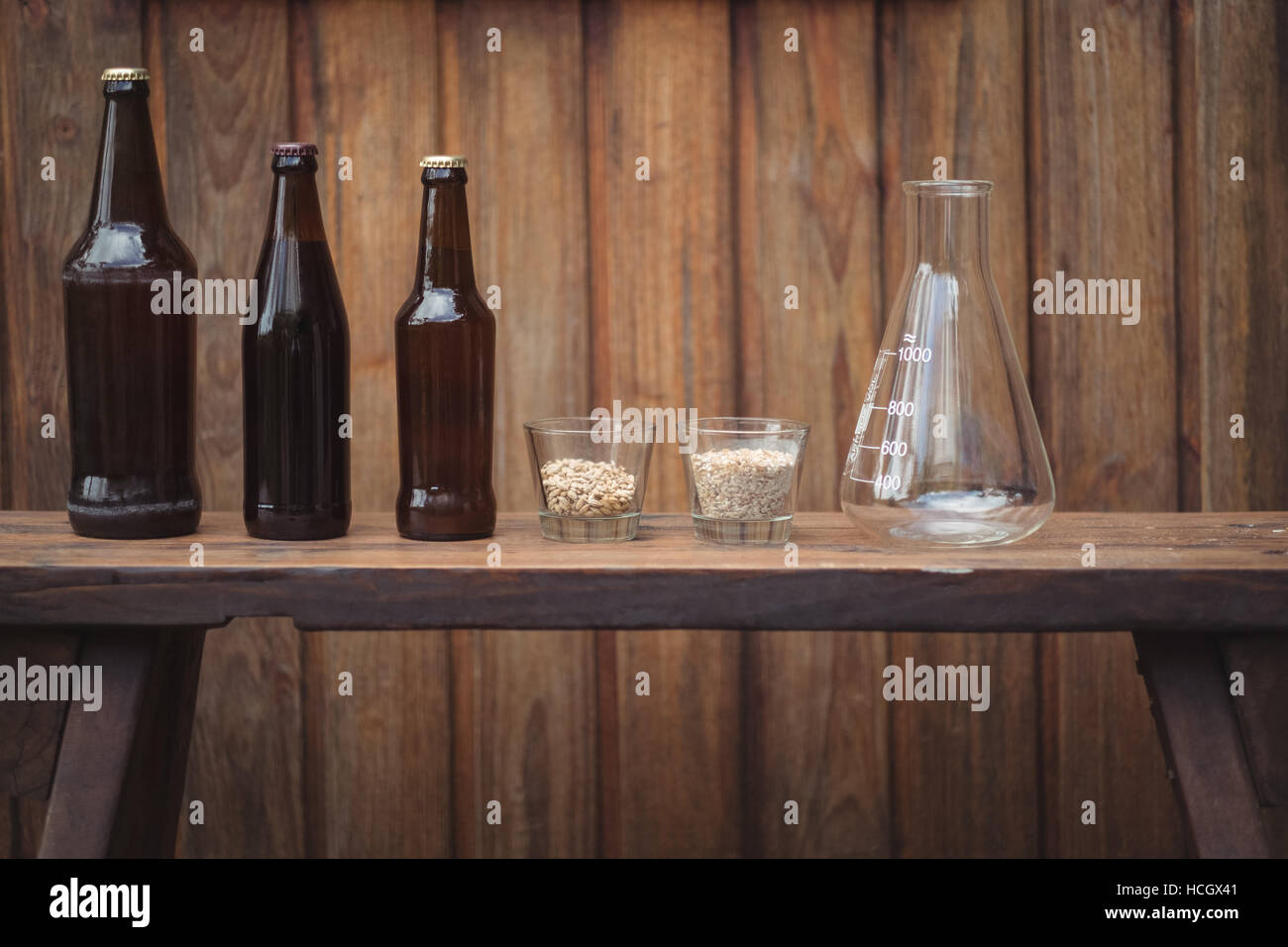 Hausgemachte Bierflaschen und Zutaten mit einem konischen Kolben Stockfoto