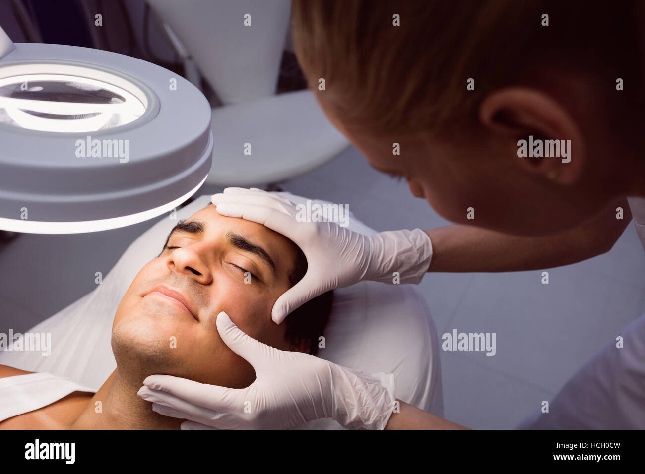 Arzt untersucht mans Gesicht für kosmetische Behandlungen Stockfoto