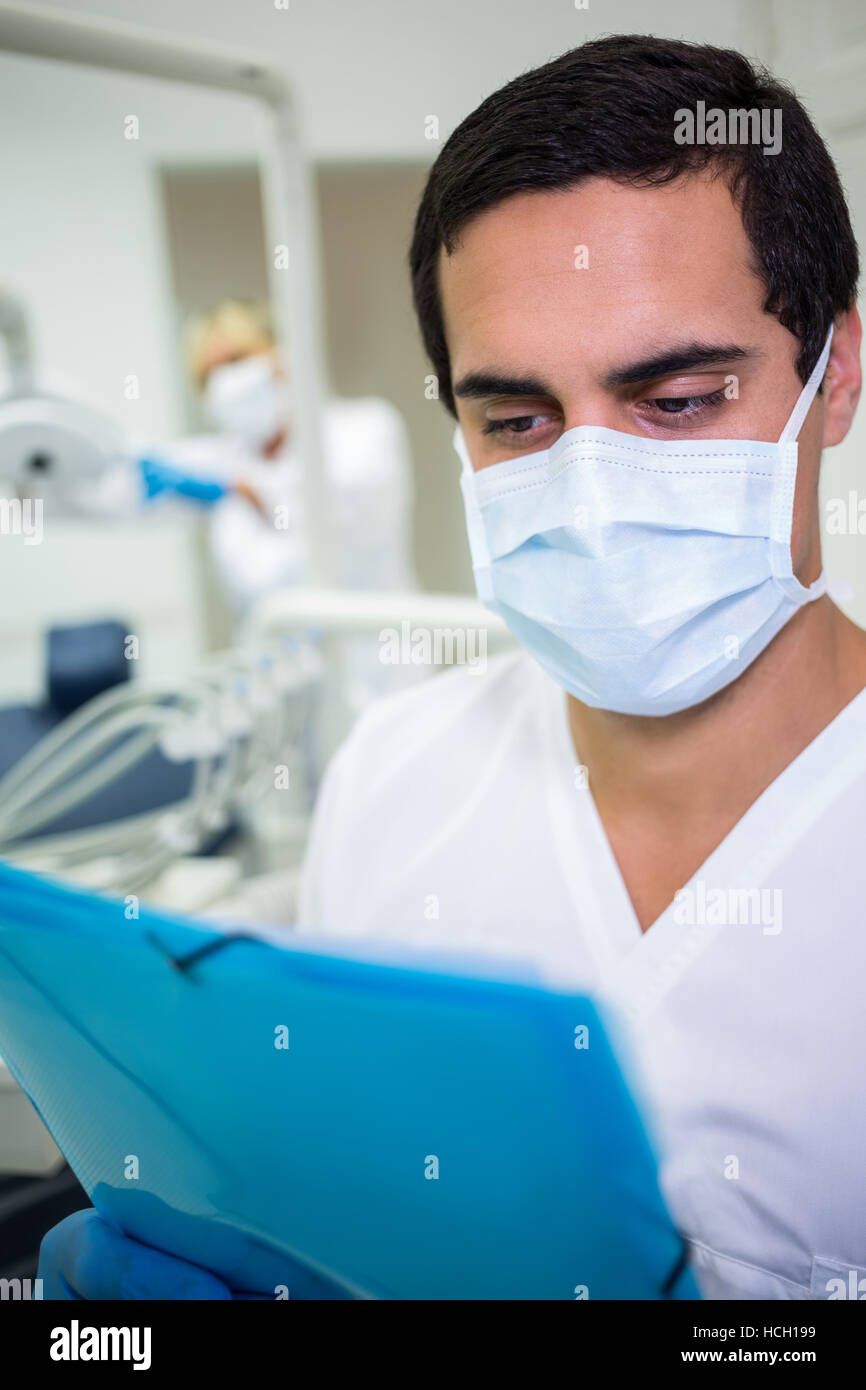 Zahnarzt in Mundschutz Blick auf eine Krankenakte Stockfoto